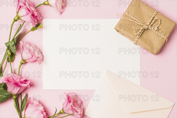 Blank paper with envelop fresh pink flower brown wrapped gift box pink background