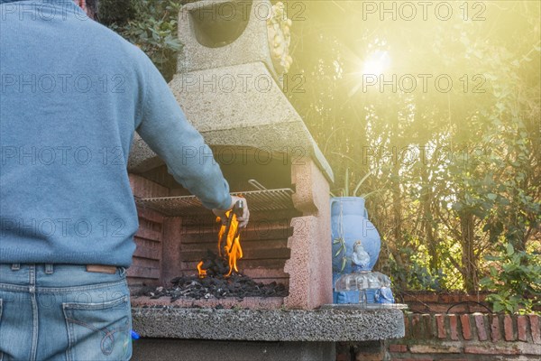 Rear view man burning coal barbecue