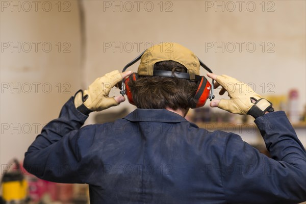 Rear view handyman wearing ear defender his ear