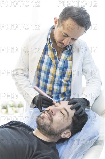 Latino man getting cosmetic treatment on his face