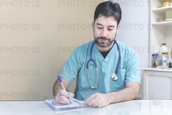 Latin doctor sitting at his desk taking notes