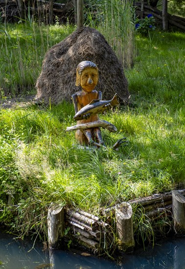 Wooden figure with fish in hands on the bank of the Spree