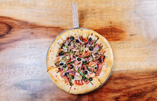 Top view of supreme pizza with olives on the wooden table. High angle view of supreme pizza with olives on wooden background