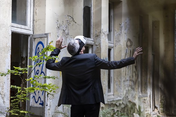 Man dressed in suit wearing VR glasses in a dilapidated office building