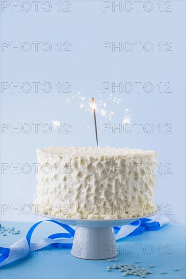 White birthday cake with burning sparkler
