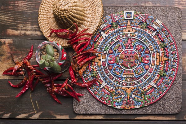 Decorative mexican symbol board near dried chili sombrero