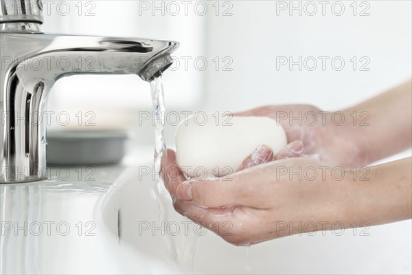 Side view hands washing bar soap sink