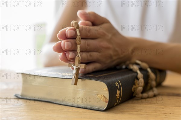 Person praying with rosary holy book