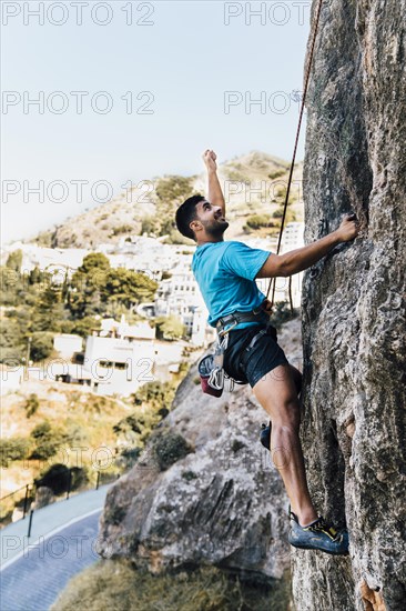 Side view sporty man climbing rock
