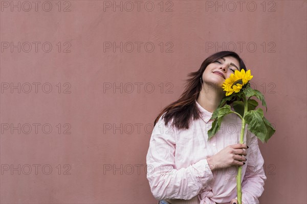 Stylish woman with sunflower hands dreaming happily