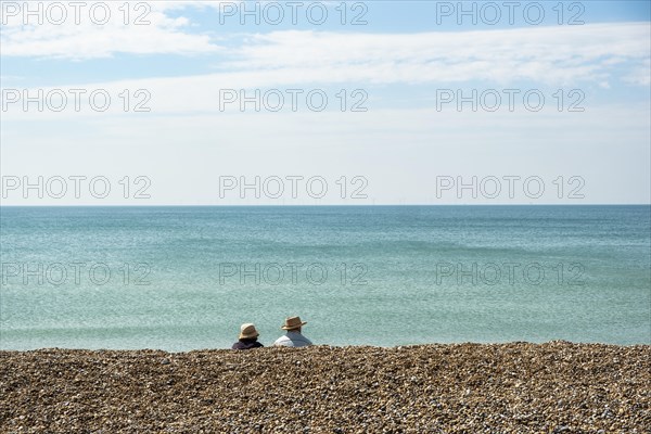 Two people sitting and looking at the sea