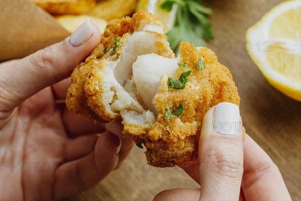 Woman breaking piece from fish chips dish