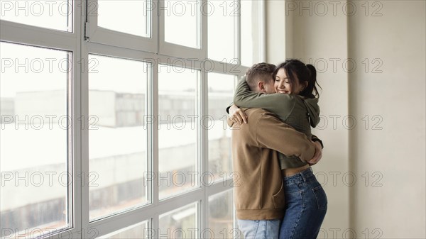 Medium shot happy couple hugging