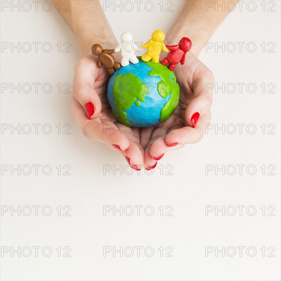 Top view hands holding globe with people figurines