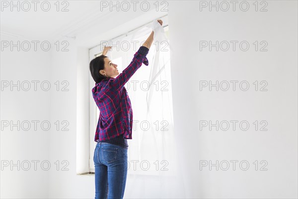 Woman hanging curtains window