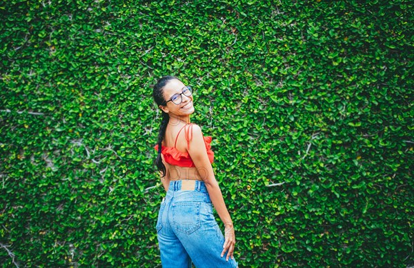 Portrait of young latin woman with leaves wall background. Portrait of attractive smiling latin girl on a wall of leaves