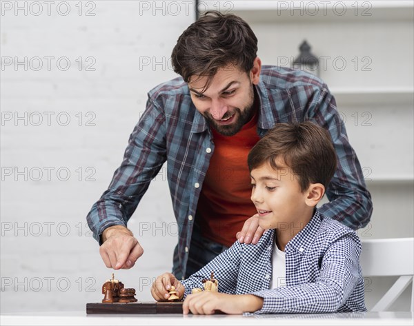 Father teaching son play chess