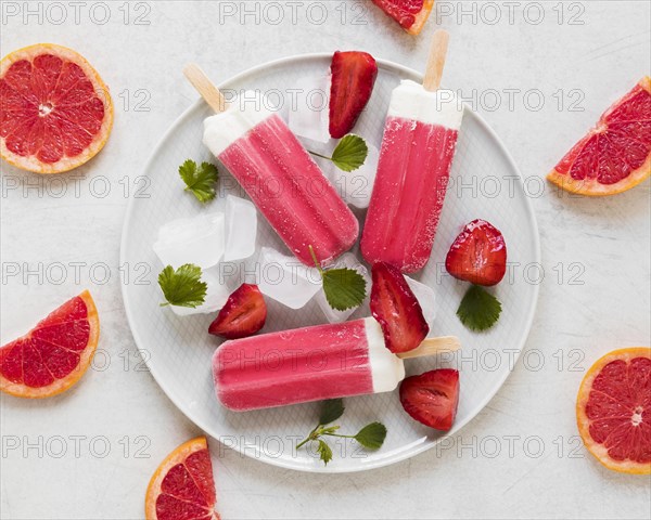 Top view yummy popsicles plate with red grapefruit