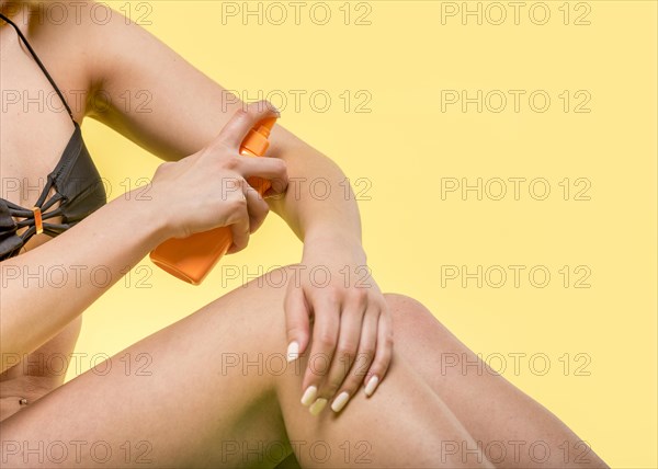 Woman sitting applying sunscreen skin