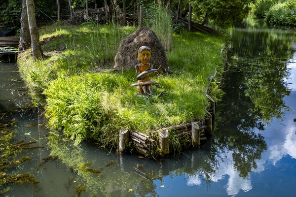 Wooden figure with fish in hands on the bank of the Spree