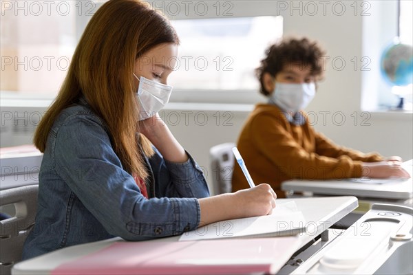 Side view children with medical masks classroom studying