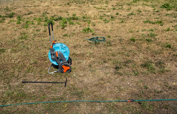 A hose reel stands on a withered meadow