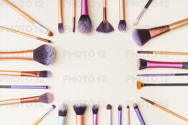 Frame made with set makeup brushes beige background