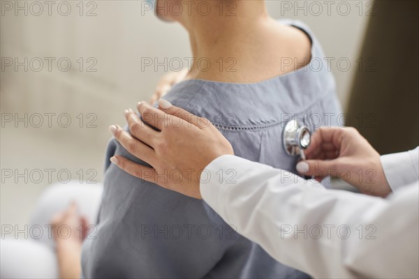 Covid recovery center female doctor checking elder patient with stethoscope