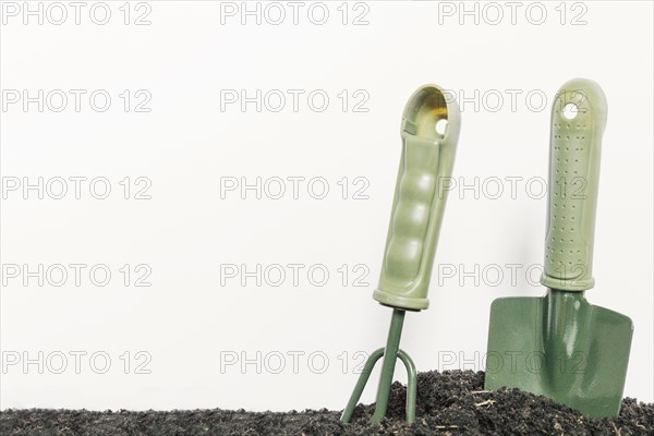 Gardening shovel gardening rake plain black soil against isolated white background