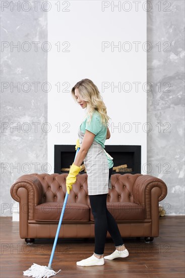 Blonde female housekeeper wiping floor mop home