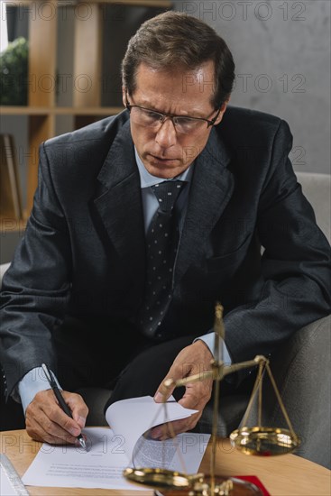 Serious mature male lawyer signing contract with pen court room