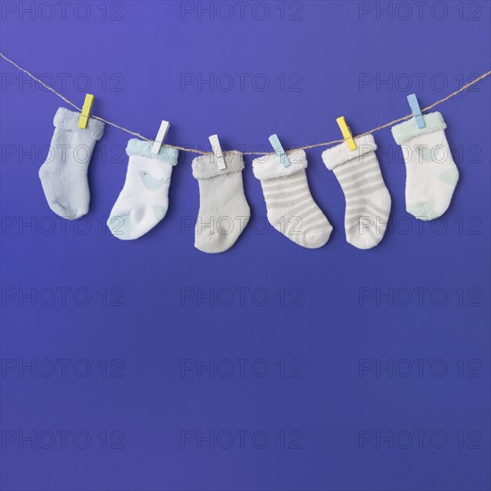 Different type baby s sock hang clothesline against blue backdrop