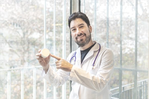 Handsome hispanic man wearing doctor uniform and stethoscope at medical clinic amazed and smiling to the camera while presenting with hand and pointing with finger