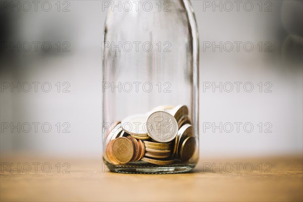 Coins glass bottle wooden surface