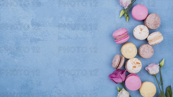 Flat lay assortment macarons with roses copy space