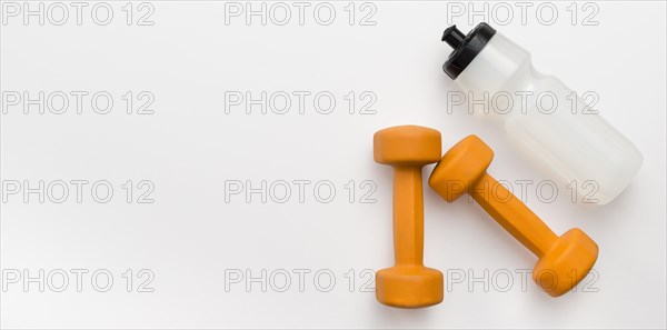 Flat lay orange weights with water bottle copy space