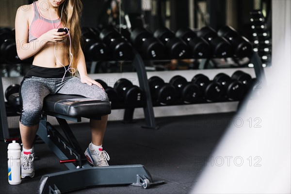 Girl with phone sitting gym