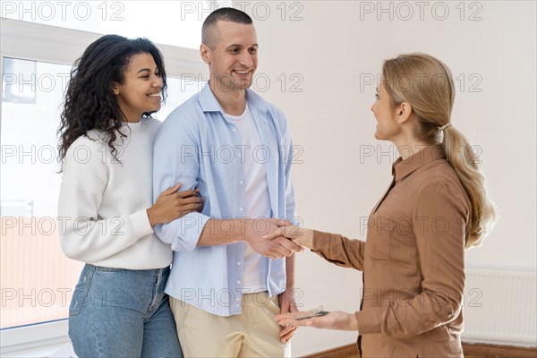 Side view realtor shaking hands with couple new house