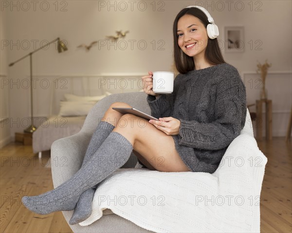 Woman cozy clothes with mug sitting armchair
