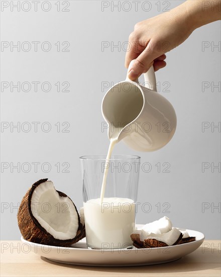 Front view hand pouring coconut milk glass