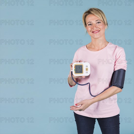 Smiling woman showing results blood pressure electric tonometer screen