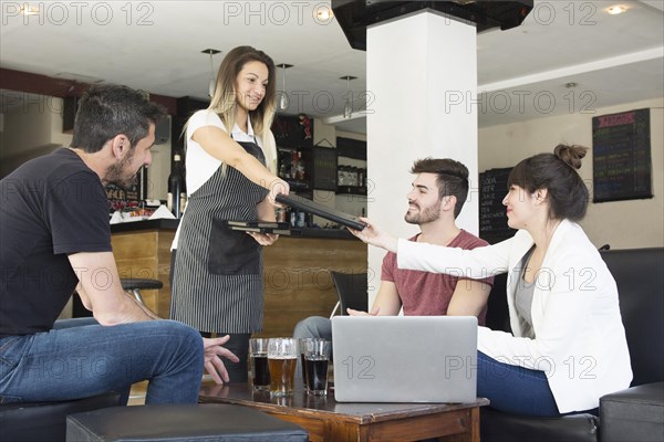 Waitress presenting menu female customer with friends bar