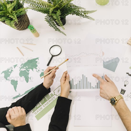 Elevated view businesspeople analyzing graph desk