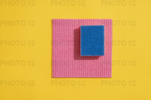 Dishcloth and dishwashing sponge on yellow background