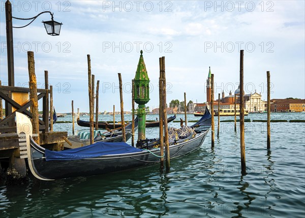 Beautiful view of traditional Venetian gondola moored by jetty and floating on waters of Grand Canal in Venice
