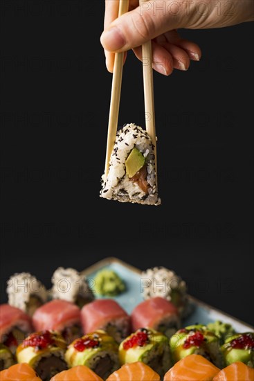 Person holding sushi with chopsticks