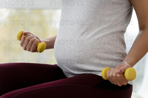 Pregnant woman using yellow weights