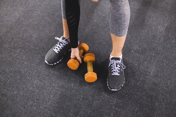 Low section view woman picking dumbbell gym