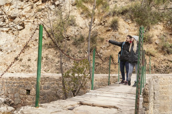 Couple with backpack walking bridge