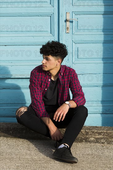 Sitting ethnic teenager checkered shirt curb